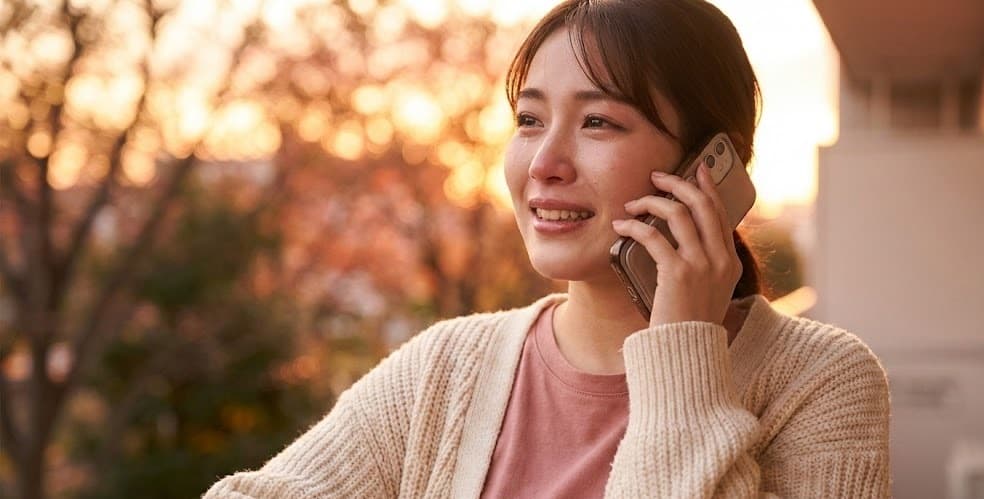 声のメッセージを聴いて感動する女性